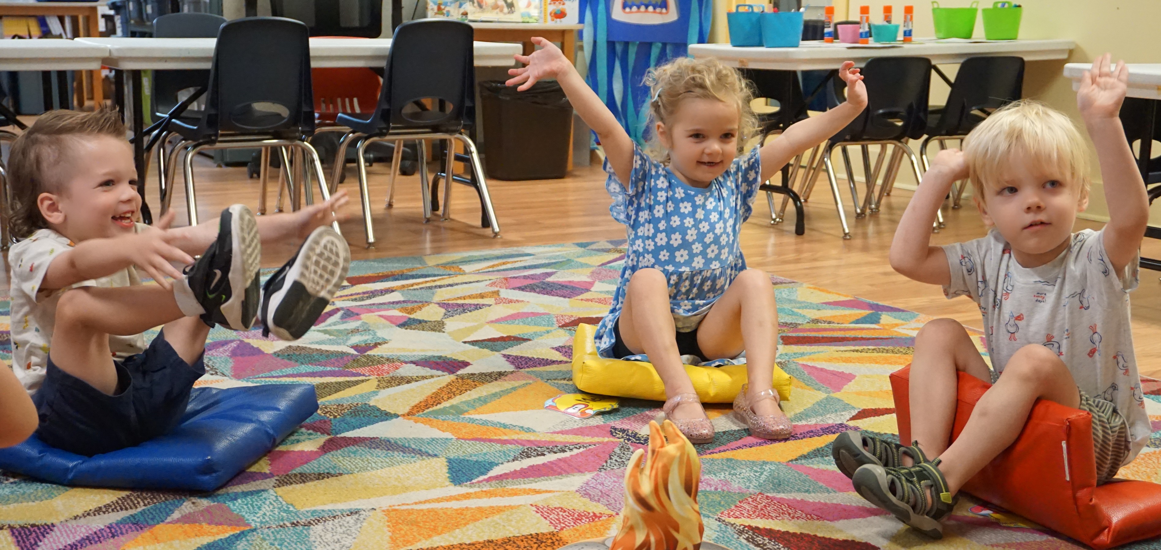 children raise hands and smile as part of a school-readiness program exclusive to the County of Brant Public Library.