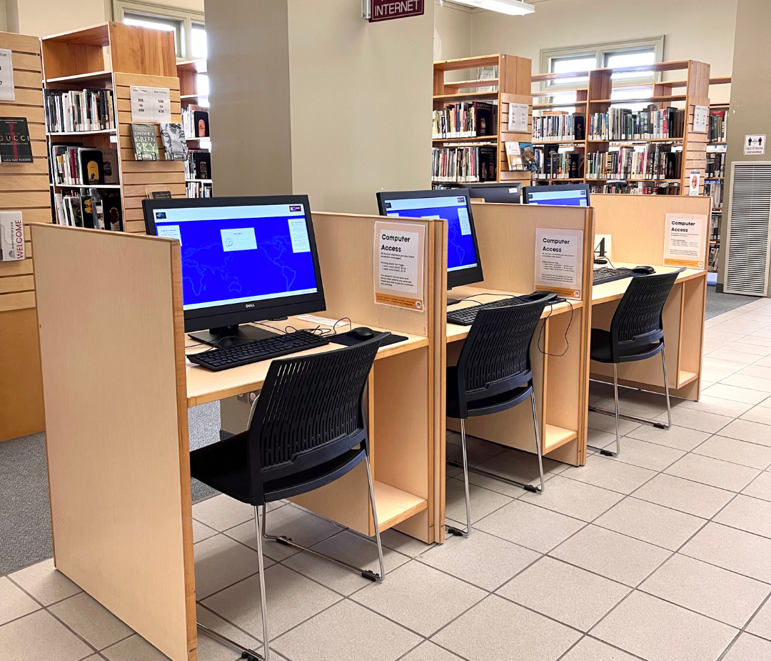 A row of three public computers in a library setting.
