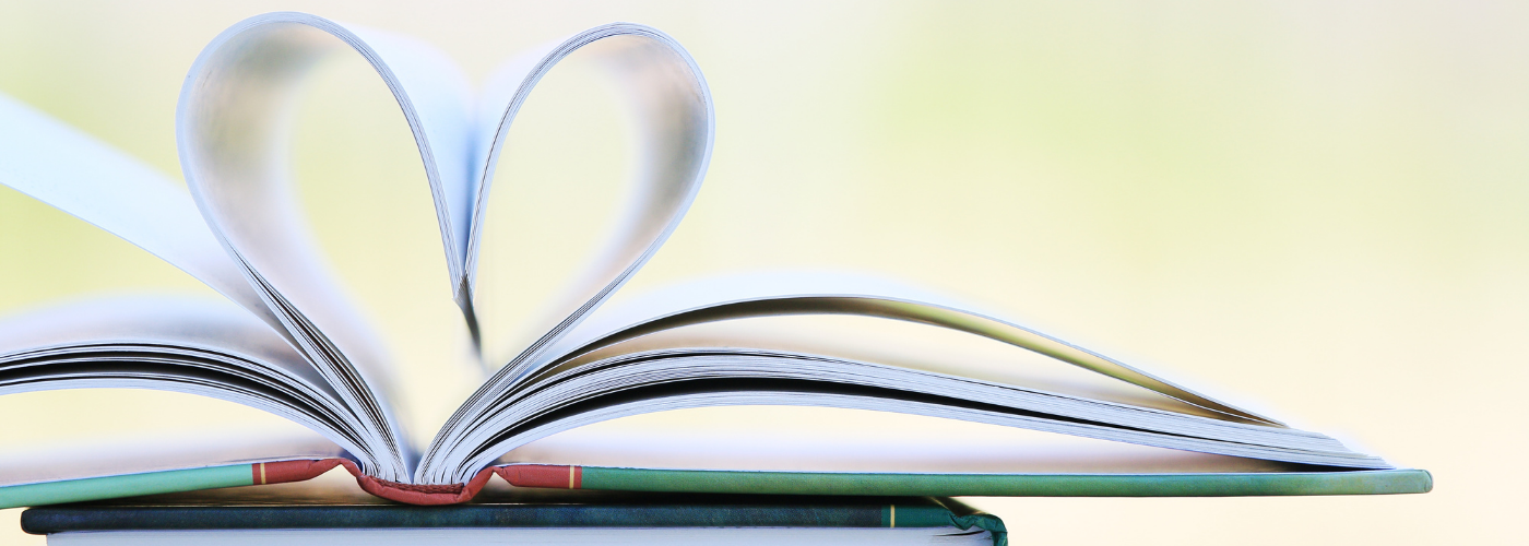 Image of book laid flat and open in middle. Two pages have been folded into the book's centre to form the shape of a heart.